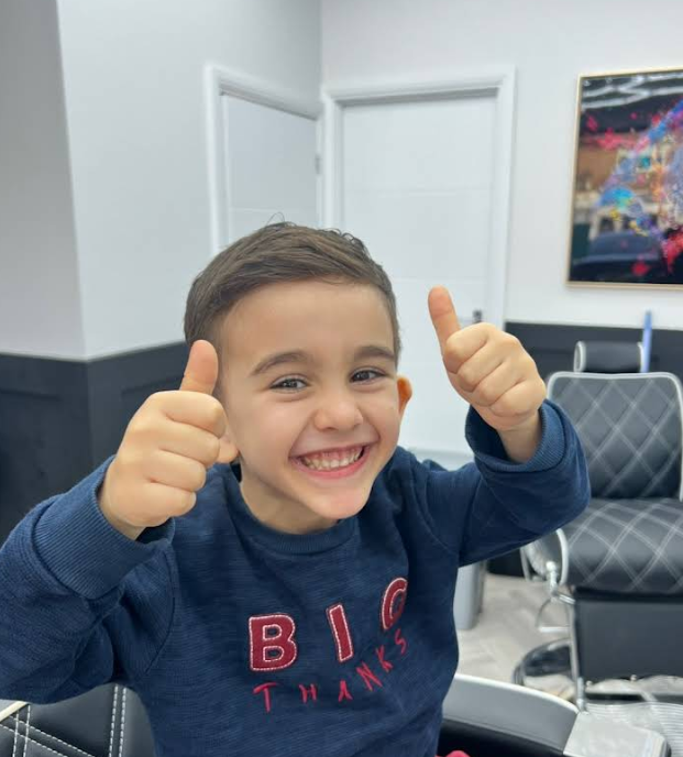 Child smiling after a haircut at Emin's Barbershop